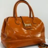 Burnt orange-patent-leather-doctor-bag-gold-buckle-nigeria Burnt orange patent leather doctor bag with gold buckle logo plate and rolled handles, Nigeria