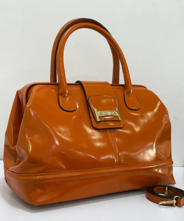 Burnt orange-patent-leather-doctor-bag-gold-buckle-nigeria Burnt orange patent leather doctor bag with gold buckle logo plate and rolled handles, Nigeria