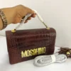 moschino-croc-embossed-flap-bag-burgundy-brown-gold-moschino-logo-chain-nigeria Moschino croc-embossed flap bag deep burgundy brown leather with bold gold MOSCHINO letter logo and chain strap Nigeria