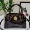 roberto-cavalli-patent-leather-top-handle-bag- burgundy-gold-medallion-studded-nigeria Roberto Cavalli patent leather top handle bag with burgundy gold crest medallion studded detail and crossbody strap Nigeria