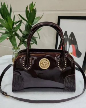 Roberto Cavalli patent leather top handle bag with burgundy gold crest medallion studded detail and crossbody strap Nigeria