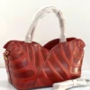 Sculptural leaf embossed leather tote bag red rust with arc top handles and gold hardware Nigeria